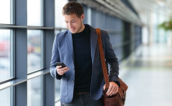 man walking through airport looking at phone
