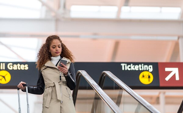 woman walking through airport looking at phone